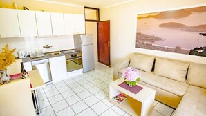 A compact living space with a kitchenette, a sofa, and a painting on the wall.