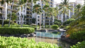 A resort with a pool, palm trees, and a multi-story building with balconies.