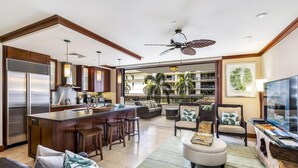 A modern kitchen with a large island, bar stools, and a dining area with a sofa and chairs.