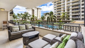 A balcony with wicker furniture, a pool, and a view of high-rise buildings.