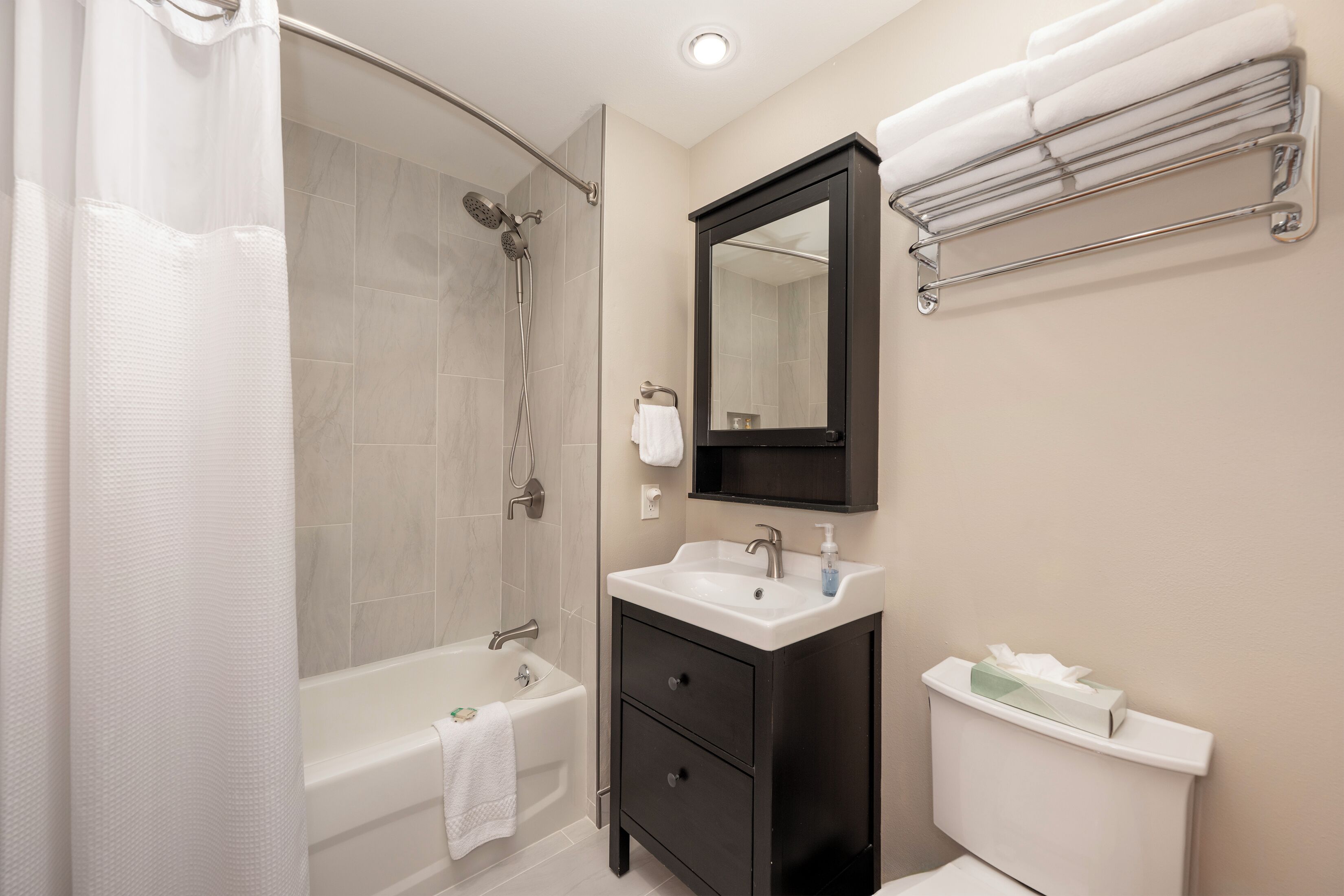 Un bagno moderno con doccia, vasca, lavabo e porta asciugamani.