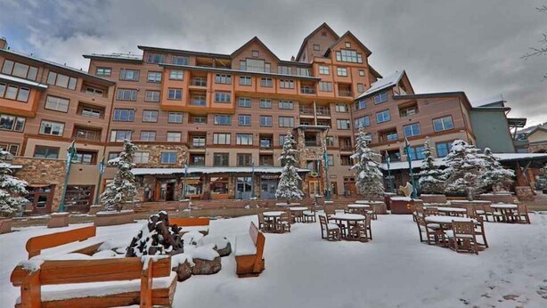 Un hôtel à plusieurs étages doté d’une cour intérieure aménagée avec des espaces de détente en plein air et des arbres couverts de neige.