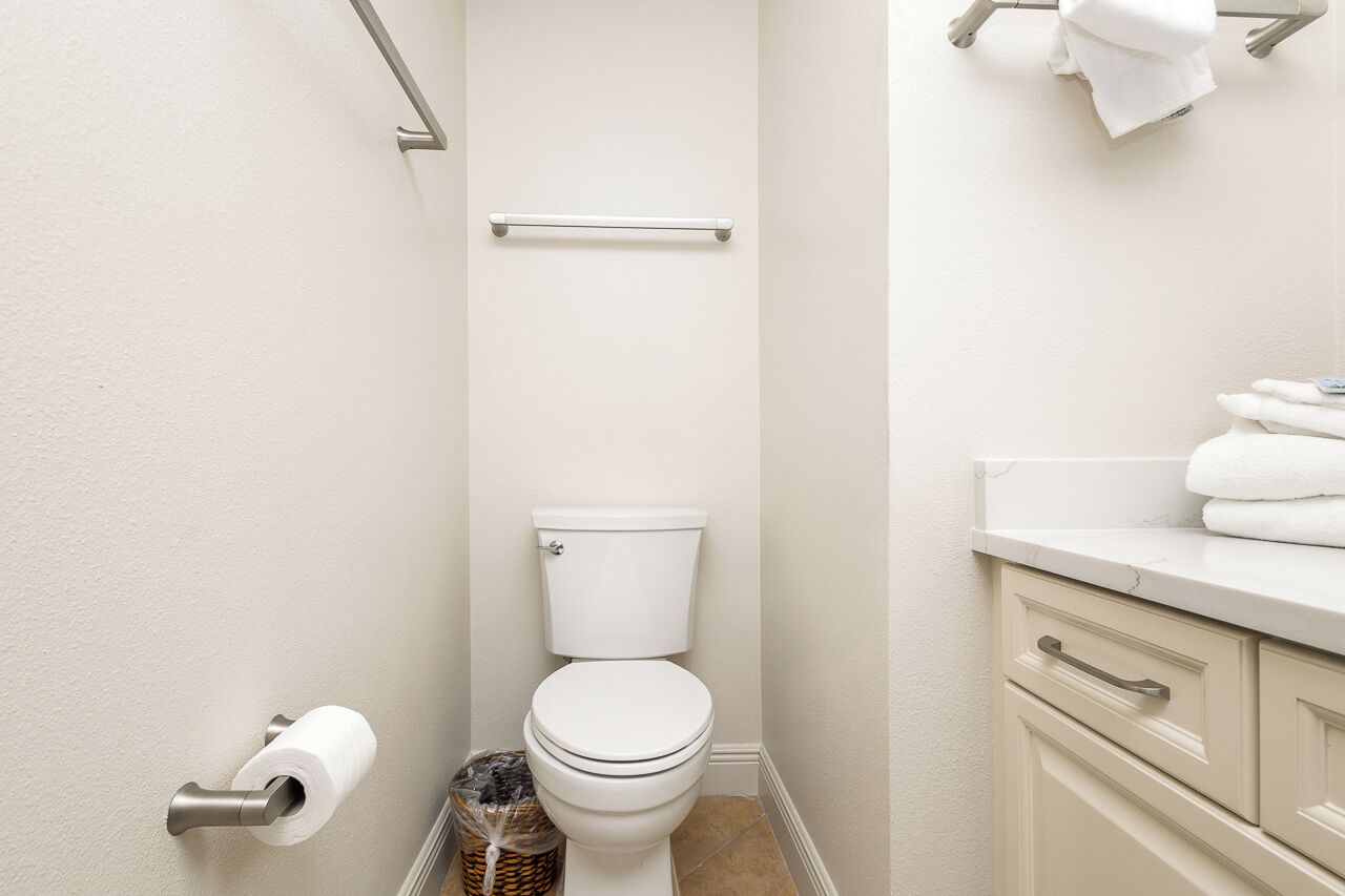 Ein kleines, sauberes Badezimmer mit Toilette, Handtuchhalter und Mülleimer.