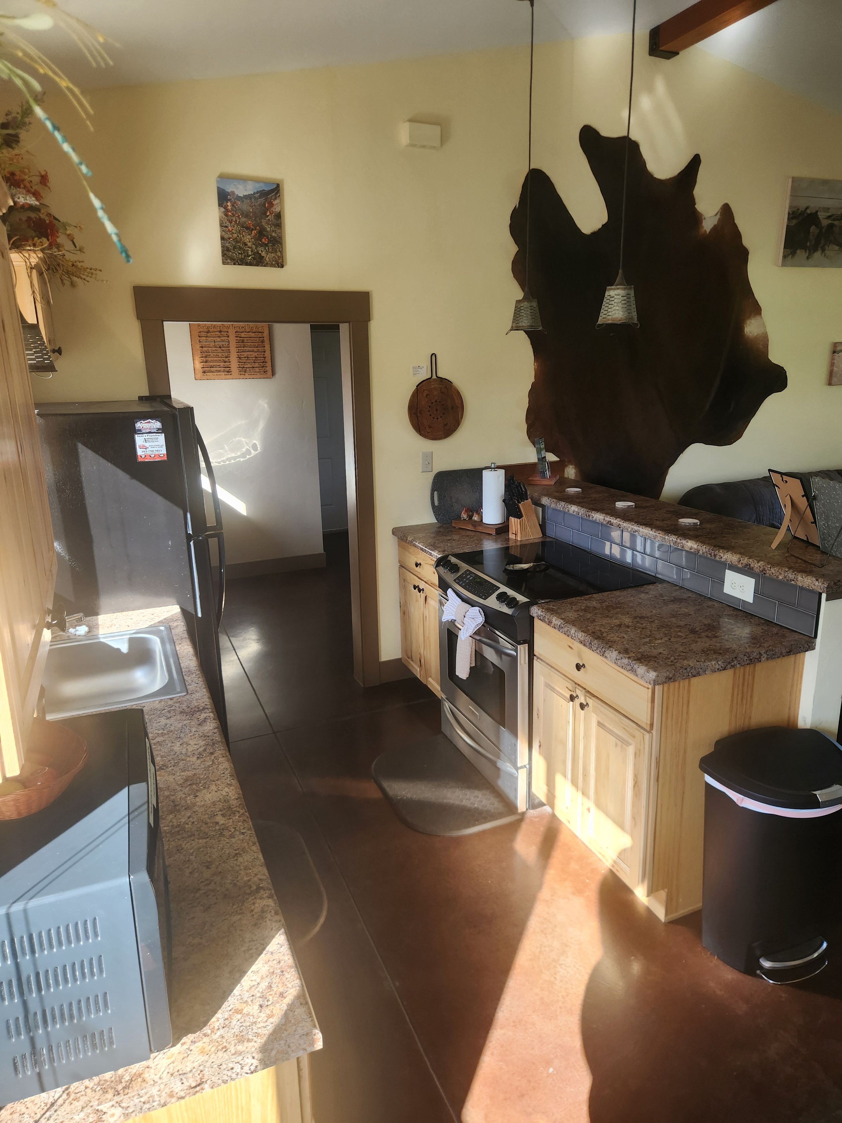 Une cuisine équipée d’un réfrigérateur, d’une cuisinière, d’un évier et de meubles de rangement en bois.