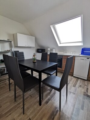 Et moderne køkken med spiseplads, med et sort spisebord, stole og et ovenlys.