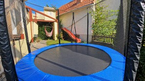 A trampoline surrounded by a safety net, with a hammock and a slide in the background. - New accommodation directly adjacent to Kassel (up to 18 pers.) (Kirchbauna)