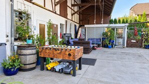 En udendørs patio med et bordtennisbord, en legetøjsbil og potteplanter.