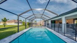 A covered swimming pool with a clear view of the surrounding area, including a house and a lawn. - Stunning! Private Villa with pool, for families. No storm damage.  (Cape Coral)