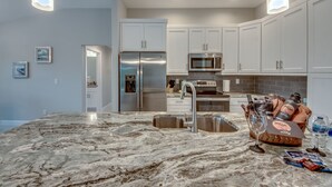 A modern kitchen with white cabinets, stainless steel appliances, and a marble countertop. - Stunning! Private Villa with pool, for families. No storm damage.  (Cape Coral)