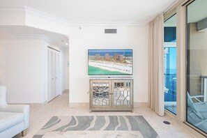 Relax in this stylish living room with a large flat-screen TV, comfortable sofa, and a door leading to another room.