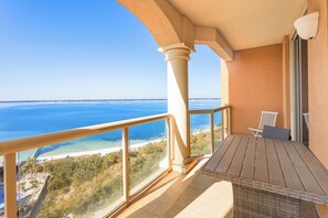 Enjoy the ocean view from this balcony with a chair and table.