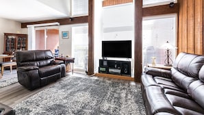 A spacious living room with a leather sofa, a television, and a wooden entertainment unit.