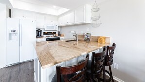 A modern kitchen with white cabinetry, a marble countertop, and a built-in stove.