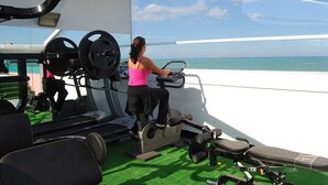 Une salle de sport équipée de matériel d’exercice et offrant une vue sur l’océan.