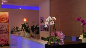 Un espace d’accueil au design moderne, comprenant un comptoir de réception, des plantes en pot et un mur orné d’œuvres d’art florales.