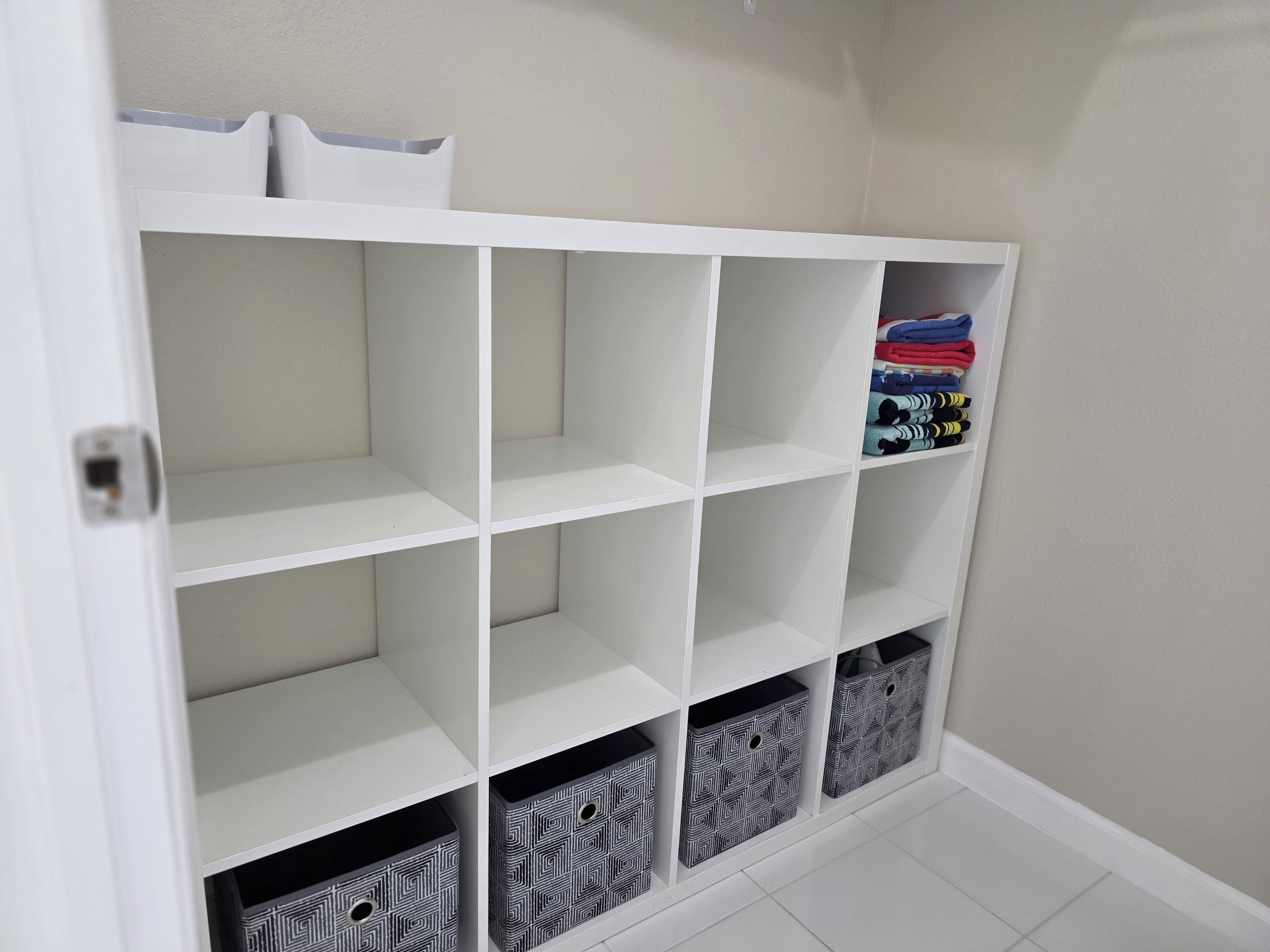 Un módulo de almacenamiento blanco con varias estanterías y cajas, algunas con ropa doblada.