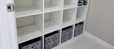 Un módulo de almacenamiento blanco con varias estanterías y cajas, algunas con ropa doblada.