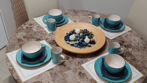 Una mesa redonda con un plato decorativo central rodeado de tazas y platillos turquesa a juego.