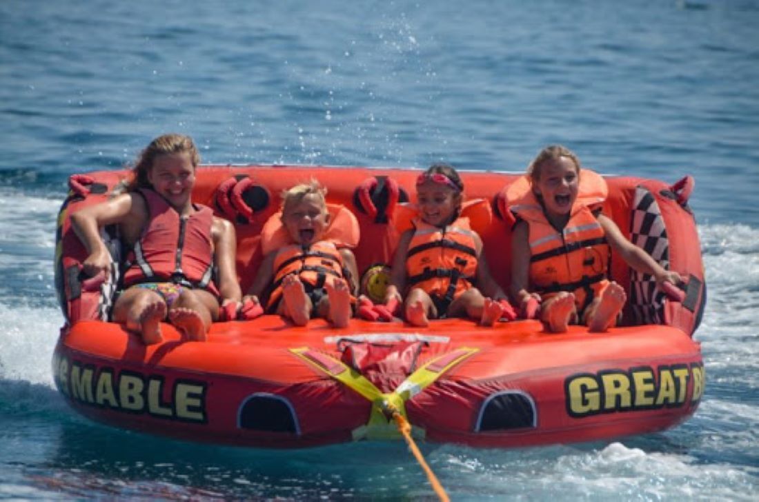 A red inflatable raft with the word "GREAT" on it, being propelled through water.