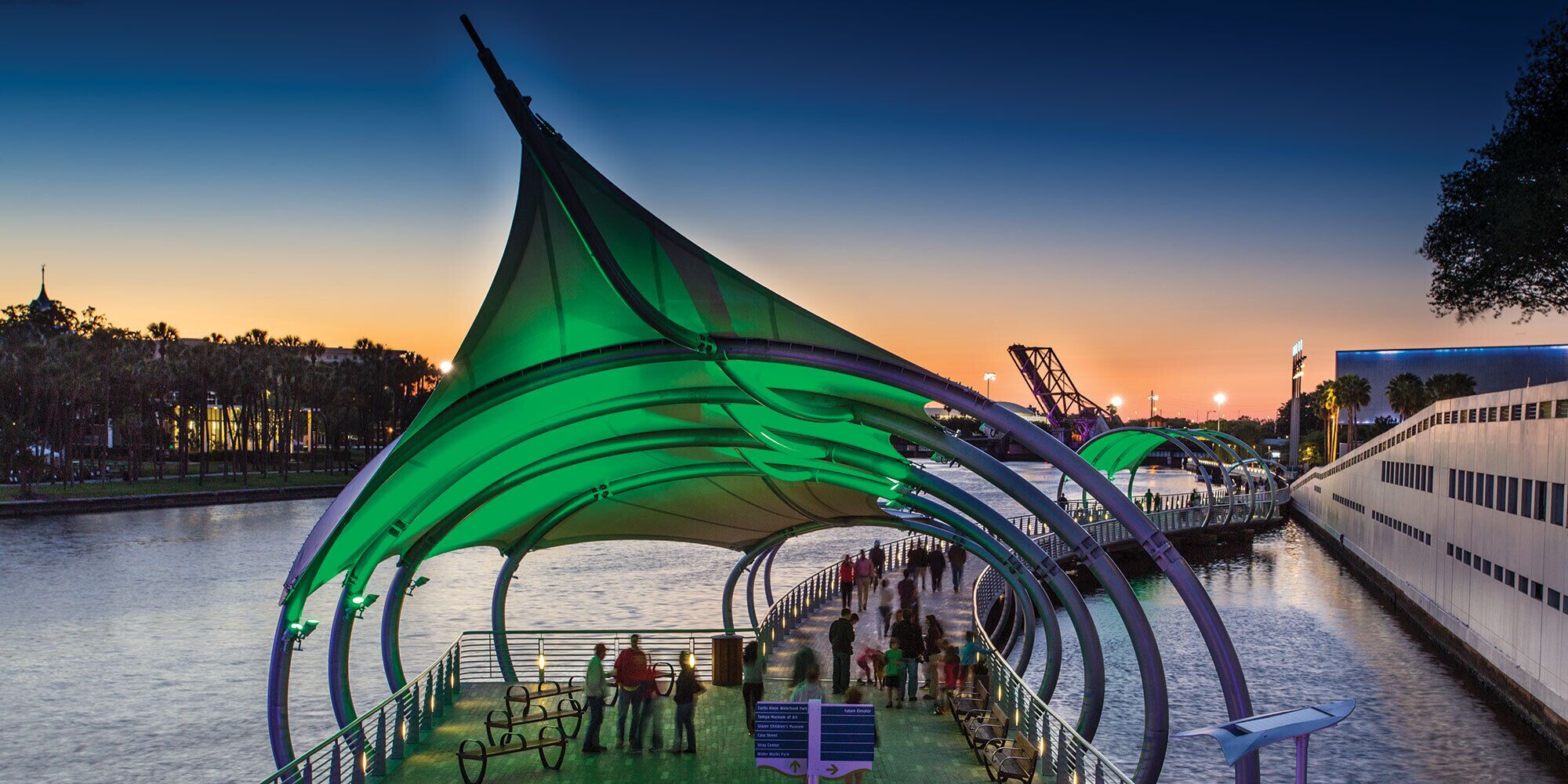 A waterfront promenade with a distinctive green canopy structure.