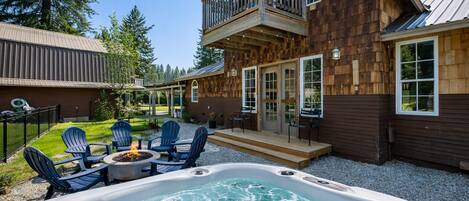 A wooden house with a hot tub, outdoor seating, and a deck.