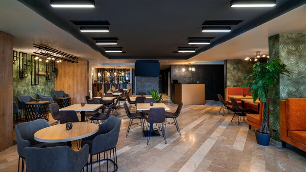 A modern hotel lobby with multiple seating areas, a reception desk, and a bar. - Labirint Hotel (Bucharest)