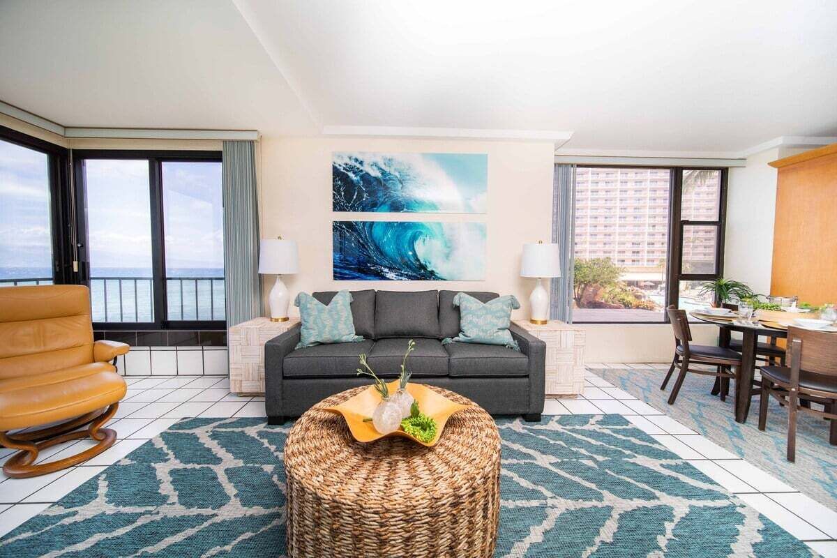 A living room with a sofa, a dining table, and a view of the ocean.