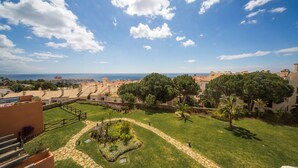 Zona residencial costera con casas escalonadas, un jardín cuidado y una vista despejada al mar.