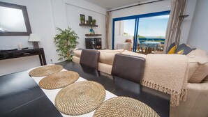Una sala moderna con una mesa de comedor negra, un sofá beige y un ventanal con vistas al exterior.