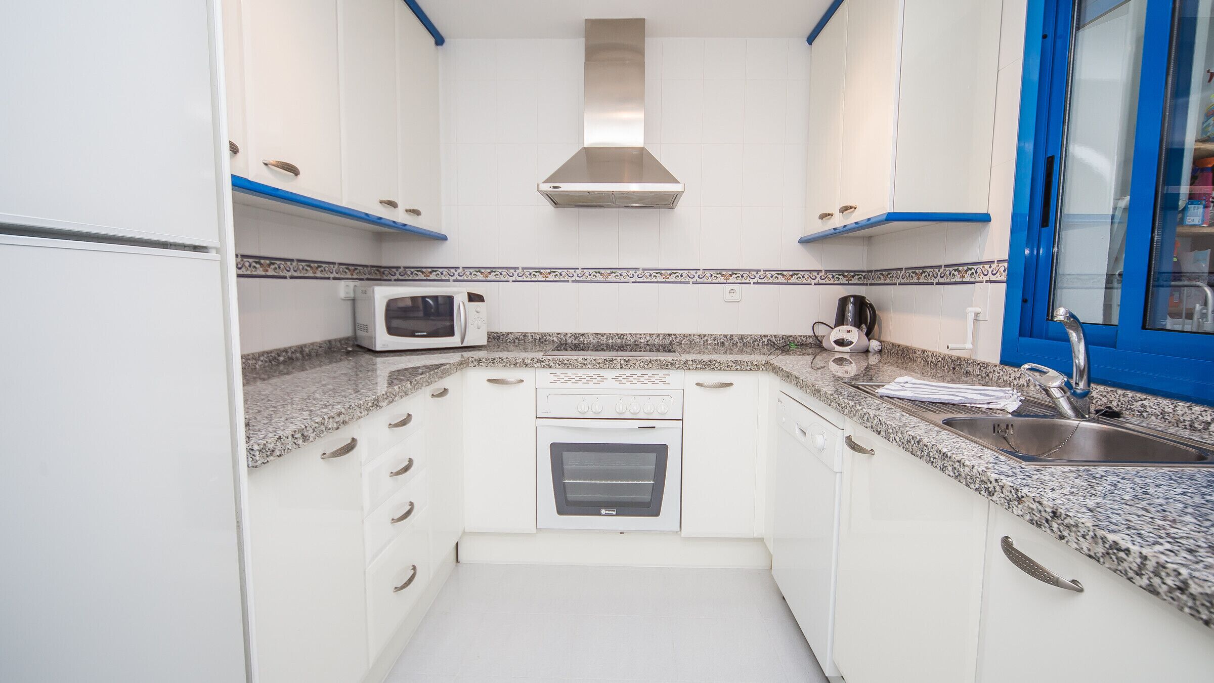 A compact kitchen with white cabinets, a microwave, a stove, and a sink.