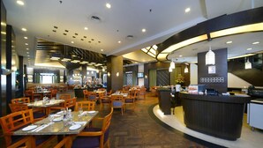 A spacious restaurant with multiple dining tables and chairs, a central bar area, and a modern ceiling design with recessed lighting. - Wonderland Villa at Port Dickson (Port Dickson)