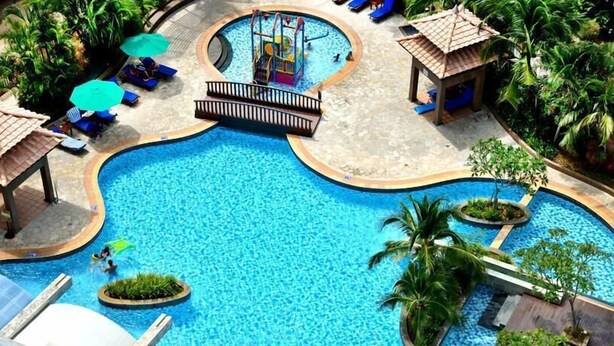 A large outdoor swimming pool with a central play area, surrounded by lounge chairs and umbrellas. - Wonderland Villa at Port Dickson (Port Dickson)