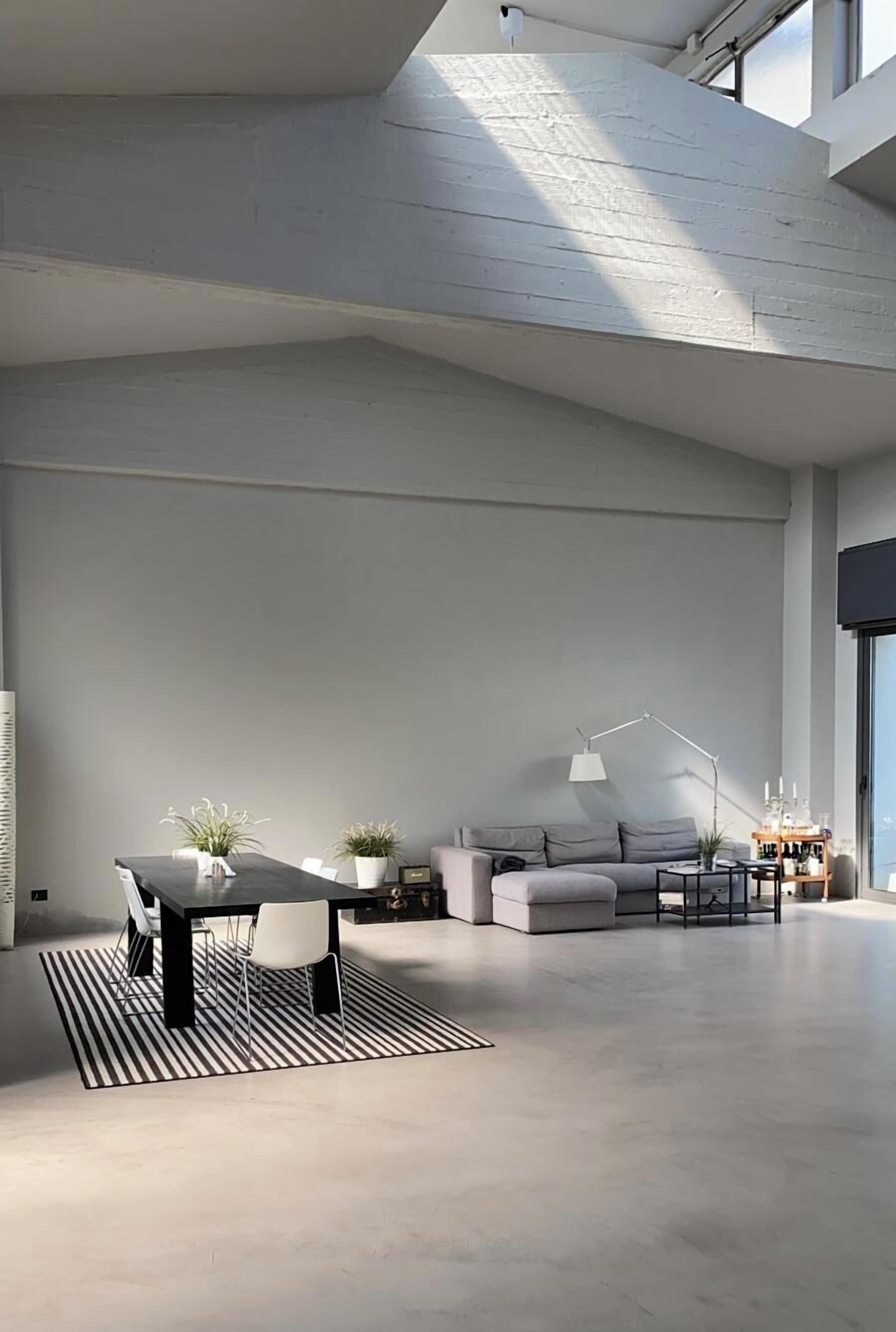 Un vaste espace de vie au design moderne, comprenant un canapé, une table à manger avec des chaises et une table basse.