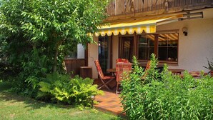 Eine Terrasse mit Holzdeck, einem Tisch und Stühlen sowie einem gelben Sonnensegel.