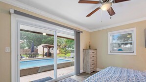 Ein Schlafzimmer mit einer großen Glasschiebetür, die zu einem Garten mit einem Pool führt.