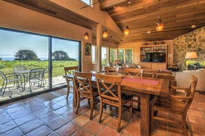 A spacious dining area with a large wooden table and chairs, a stone fireplace, and a television set.