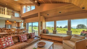 A spacious living area with a high ceiling, large windows, and a view of the outdoors. - Wild Moor - Hot Tub & Star View Retreat (Sea Ranch)