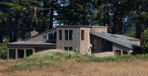 A modern house with a sloped roof, large windows, and a wooden exterior.