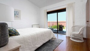 A bedroom with a bed, a chair, a radiator, and a view of a pool and garden. - Sítio do Louro Villa - Deluxe Villa w/ gaming room (São Martinho do Porto)