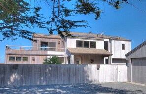 Ein zweistöckiges Haus mit Balkon, Garage und umzäunter Garten.