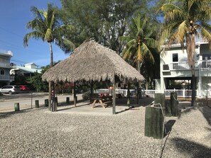 Relax in a serene gazebo surrounded by palm trees and a multi-story building.