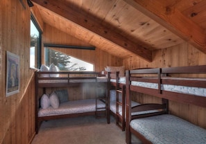 A cabin with bunk beds, a window with a view, and a poster on the wall. - Point of View | Dog-Friendly Oceanfront Escape (Sea Ranch)