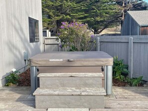 A hot tub with a cover, steps leading up to it, and a wooden deck. - Point of View | Dog-Friendly Oceanfront Escape (Sea Ranch)