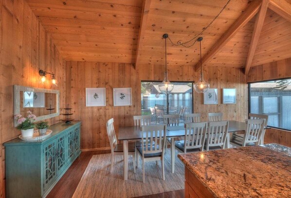 A wooden interior with a dining area, a cabinet with decorative items, and a large window. - Point of View | Dog-Friendly Oceanfront Escape (Sea Ranch)