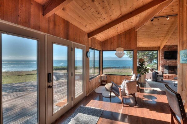 A spacious room with large windows, a wooden ceiling, and a view of the ocean.