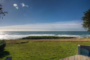 A grassy area with a wooden deck and a view of the ocean. - Point of View | Dog-Friendly Oceanfront Escape (Sea Ranch)