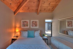 A bedroom with a bed, bedside tables, a dresser, and artwork on the walls.