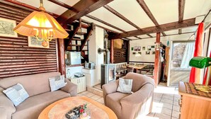 Uma sala de estar acolhedora com teto de madeira, área de jantar e cozinha.