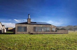 A modern house with a flat roof, large windows, and a chimney.