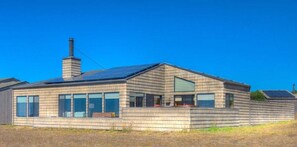 A modern house with a sloped roof, large windows, and a chimney. - Seale - Sea Ranch 2BR Oceanfront Home (Sea Ranch)